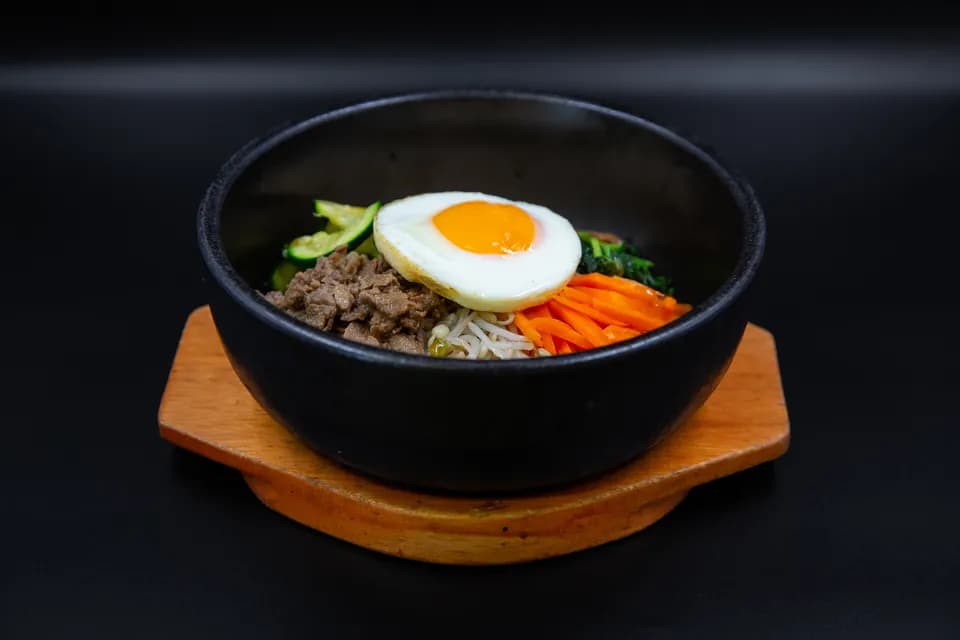 Bibimbap im schwarzen Steintopf mit Spiegelei, Rindfleisch und Gemüse
