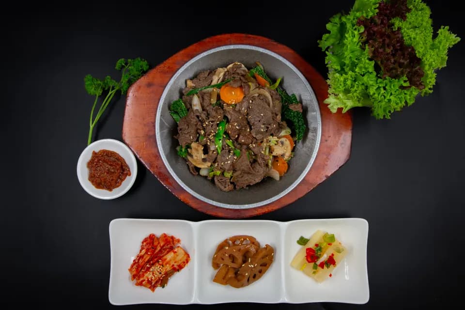 Rindfleisch-Bulgogi in der Pfanne mit Kimchi und weiteren Beilagen