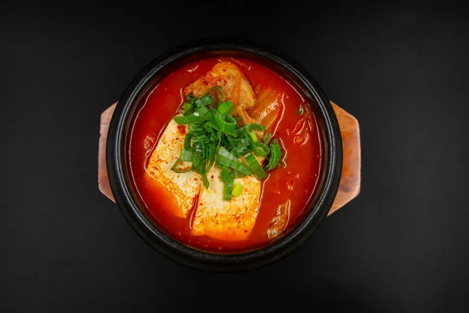 Kimchi-Eintopf mit Tofu und Frühlingszwiebeln im Steintopf