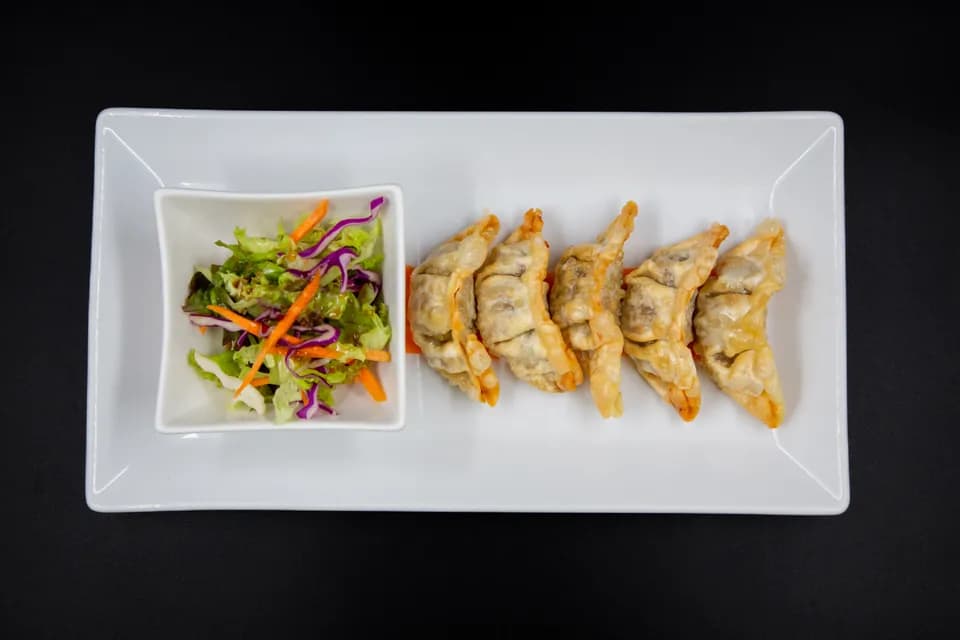 Fünf goldbraun gebratene Mandu mit kleinem Salat