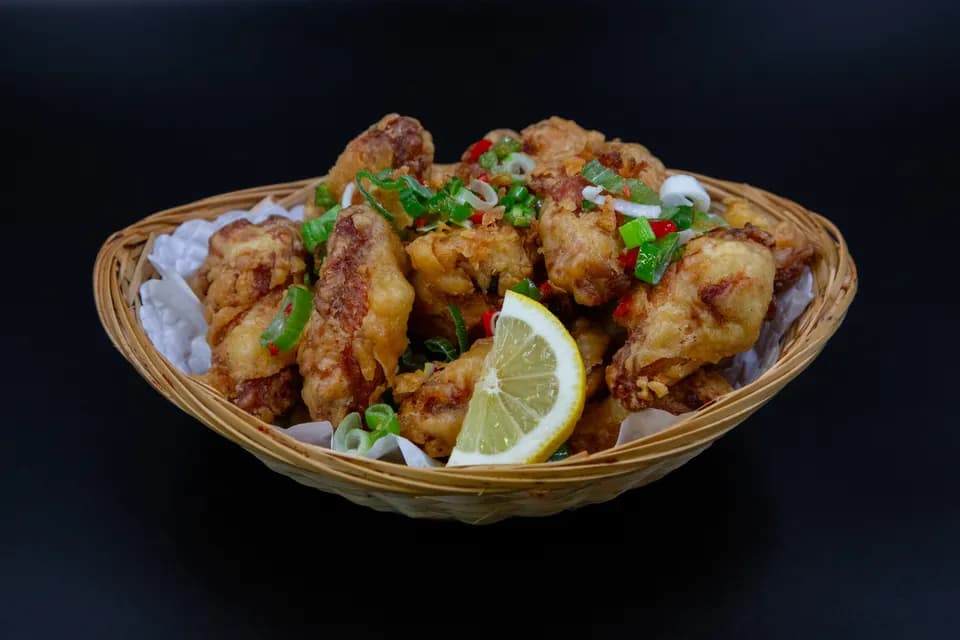 Knusprig frittiertes Poulet im Korb mit Zitrone und Frühlingszwiebeln